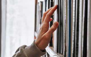 Fotografía a color de una mano buscando un libro de una librería